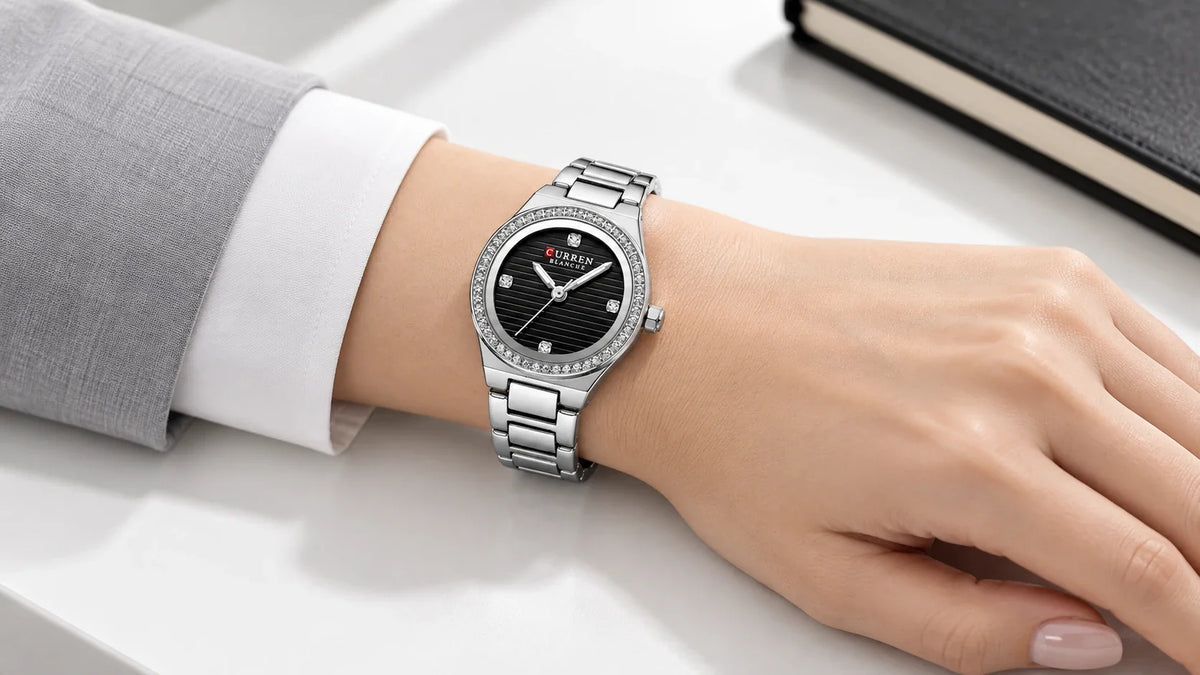 Montre femme Minoran 9101 argentée à cadran noir portée avec une chemise blanche et une veste grise.