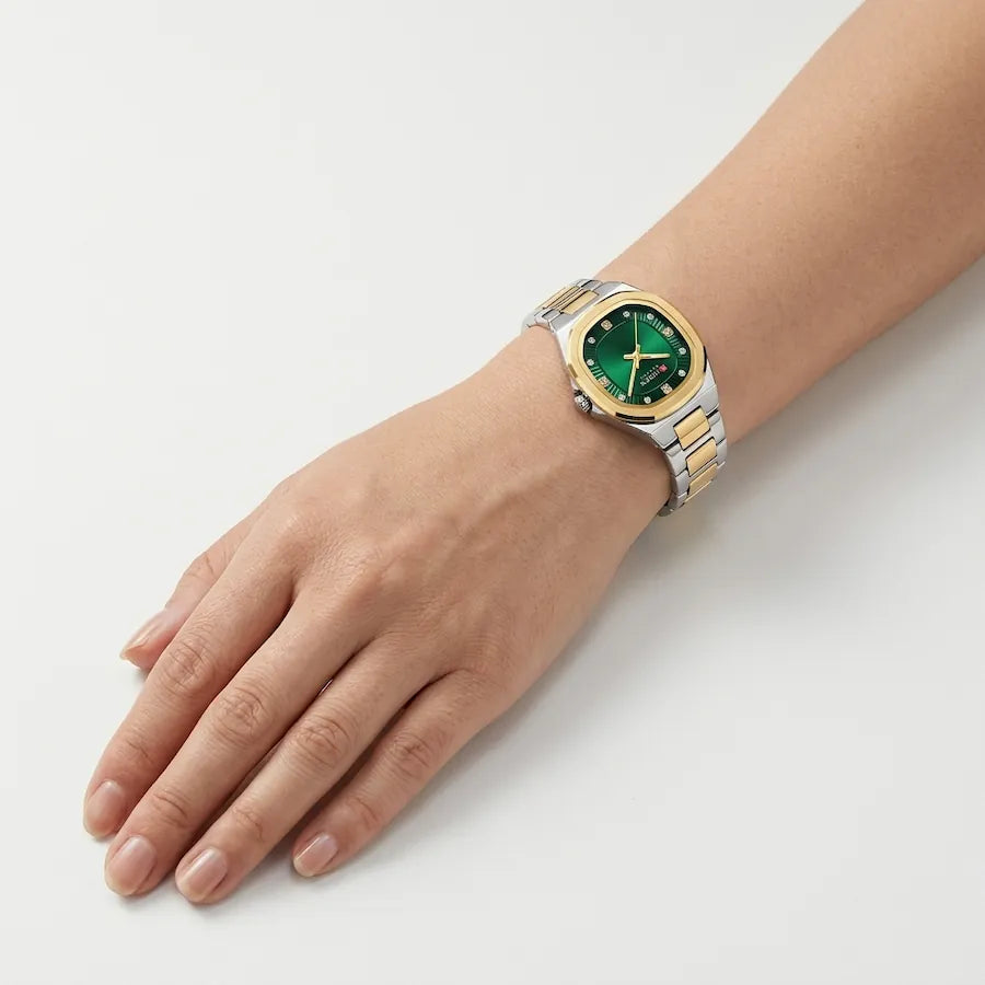 Montre femme bicolore à cadran vert Minoran 9101, portée au poignet, main posée sur une table