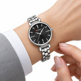 Montre femme argentée à cadran noir Minoran 9098 portée avec une chemise blanche