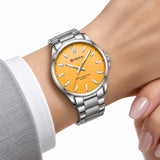 Détail au poignet de la montre femme argentée Minoran 9090 à cadran orange