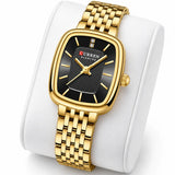 Montre femme dorée Minoran 9093 à cadran noir présentée sur un coussin blanc