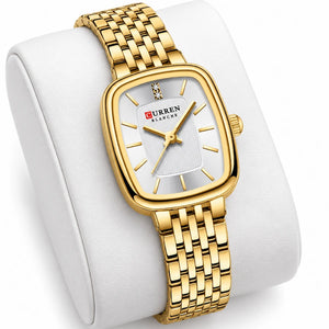 Montre femme dorée Minoran 9093 présentée sur un coussin blanc, avec son cadran rectangulaire visible