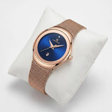 Montre femme or rose Minoran NF5004 à cadran bleu présentée sur un coussin blanc
