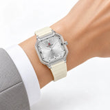 Montre Minoran NF6108, bracelet silicone crème, cadran argenté, portée au poignet avec une veste grise