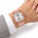 Montre Minoran NF6108, bracelet silicone rose, cadran argenté, portée au poignet avec une veste grise