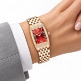 Montre Minoran PD-1737 dorée à cadran rouge au poignet avec un blazer